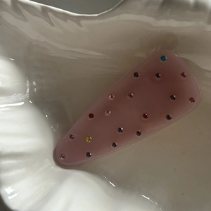 Close-up of pink duckbill hair clip decorated with colorful rhinestones on ceramic base