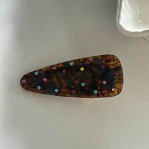 Detailed close-up of tortoise shell pattern hair clip with colorful rhinestones inlay