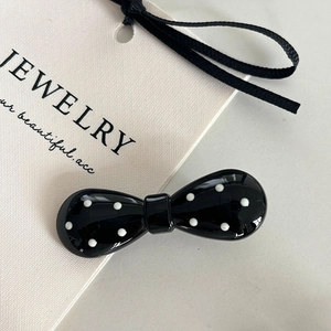 Gros plan d'une pince à cheveux noire à pois blancs sur une carte d'exposition