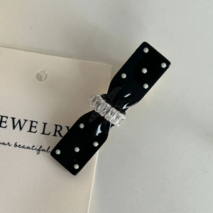 Detail of polka dot bow hair clip with crystal accents and black resin finish