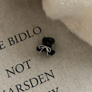 Detail of a mini black hair claw clip with a delicate silver wire bow on fabric background