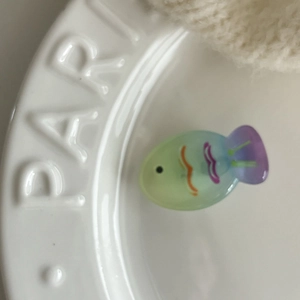 Close-up of translucent gradient fish hair clip with wavy patterns on a ceramic dish