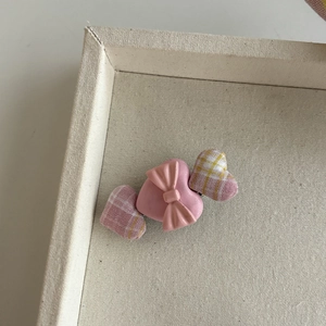 Pink heart hair clip with ribbon plaid bow design for women on a cream fabric tray