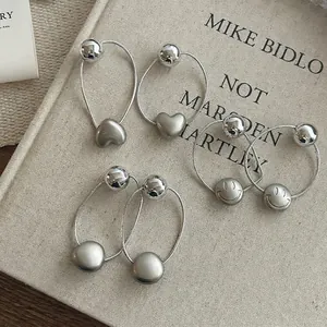 Lot de trois boucles d'oreilles argentées avec charms cœur, sphère et motif smiley