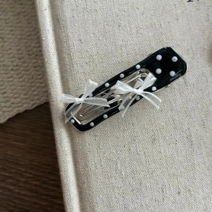 Gros plan d'une pince à cheveux noire à pois avec des nœuds en dentelle blanche