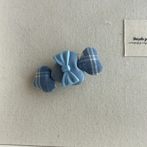 Detailed view of blue plaid bow hair clip with heart-shaped fabric and candy-like design