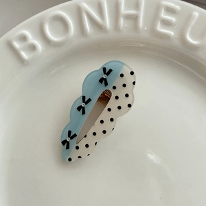Gros plan sur la barrette nuage bleue et blanche avec motif nœud et pois noirs