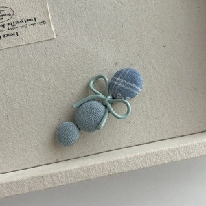 Detailed macro view of blue plaid fabric bow hair clip and button decor on display