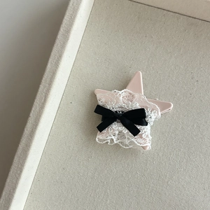 Détail de la pince à cheveux en forme d'étoile avec dentelle blanche et nœud en satin