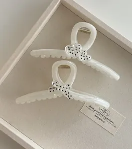 Vue détaillée de pinces à cheveux en résine blanche avec motifs de cœur et nœud à pois