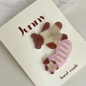 Gros plan de barrettes mignonnes avec ours brun et cœur rose sur carte de présentation