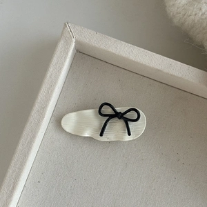 Elegant beige polka dot bow hair clip with textured resin finish on canvas tray