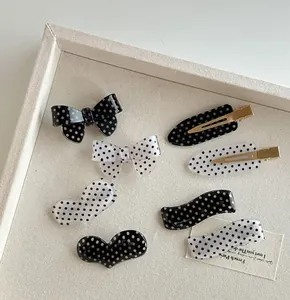 Detail of assorted polka dot bow and geometric hair clips on a textured tray