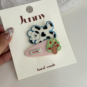 Détail d'une pince à cheveux chien mignon avec décor pomme sur carte de marque