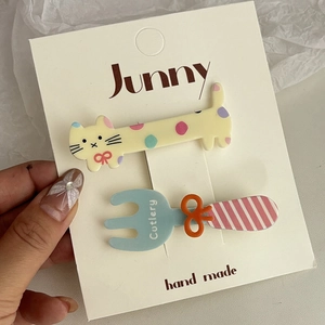 Détail de barrettes mignonnes en forme de chat et de fourchette bleue sur carte