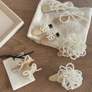 Handwoven straw hair clip set with white pearls in bow design on a wooden surface