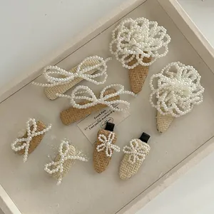Detail of elegant pearl woven hair clips with bow and flower designs on a wooden tray