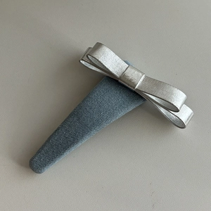 Denim bow headband with metallic silver ribbon on grey woven fabric background