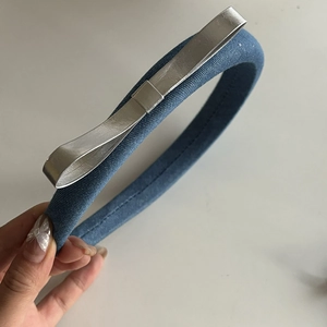 Detailed view of the blue denim headband with a stylish silver metallic bow decoration