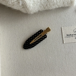Macro view of a polka dot bow hair clip with gold metal base on canvas fabric