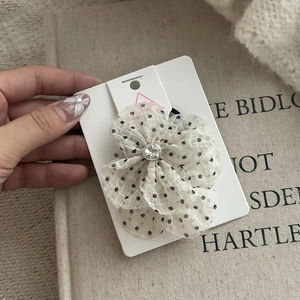 Close-up of cream polka dot mesh flower hair tie with a sparkling crystal center