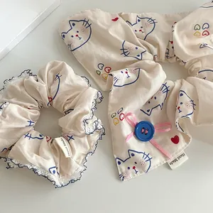 Makro-Detail von beige Spitzen-Haargummis mit Katzenprint und handgefertigtem Etikett