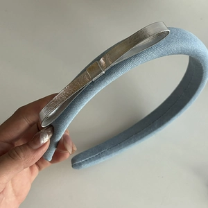 Detail showing the light blue fabric headband with a stylish silver metallic bow decoration