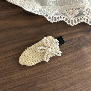 Detailed close-up of handmade straw woven hair clip with elegant pearl flower design