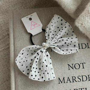 Detail of polka dot chiffon bow hair tie with pearl accent on a vintage book
