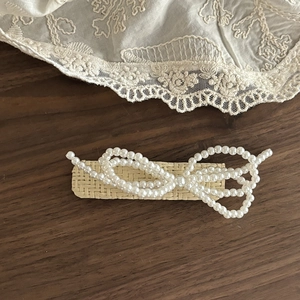 Detailed close-up of woven rattan hair clip with a multi-layered pearl bow design