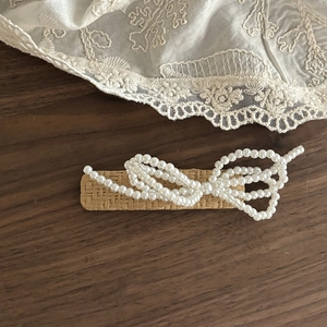 Macro shot of woven rattan hair clip with delicate pearl bow on vintage lace background