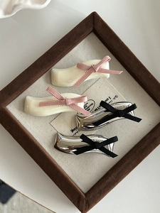 Detailed view of four retro bow hair clips in cream white and metallic silver finishes