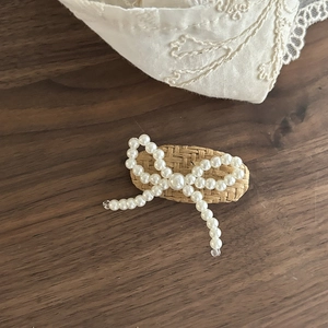 Detail of beaded pearl bow hairpin on woven backing with metal duckbill clip