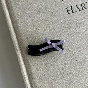 Elegant wavy black hair clip with light purple ribbon bow on a textured background