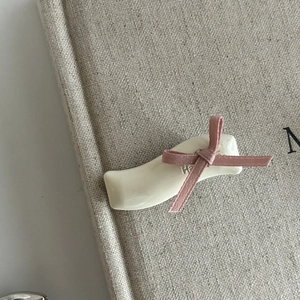 Detailed shot of cream-colored resin hair clip with pink velvet bow and letter detail