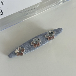 Detail of blue knit hair clip featuring three silver metal flowers with heart centers