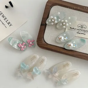 Détail de barrettes en acétate bleu avec perles, nœuds ruban et motifs papillons