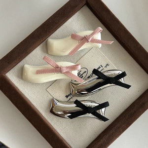 Bow hair clips in cream and silver with pink and black ribbons on a wood board