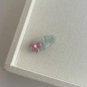 Détail d'une pince à cheveux en acétate marbré avec nœud rose et perle blanche