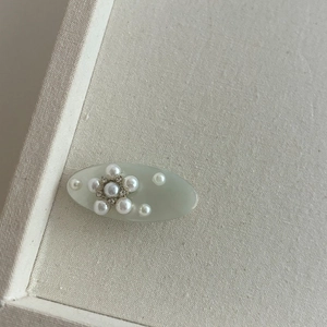 Détail d'une pince à cheveux bleue en acétate avec perles et strass sur beige