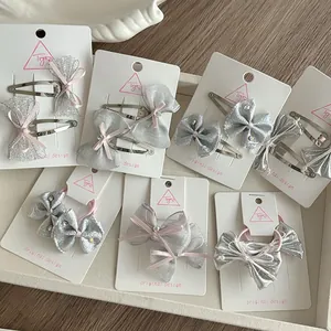 Detail of silver mesh and pink ribbon bow hair clips and elastic ties on card