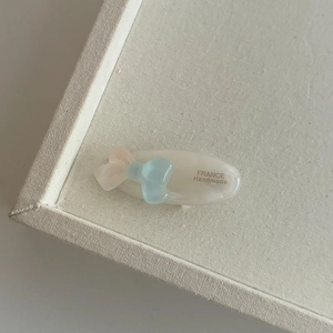 Détail d'une pince à cheveux papillon en acétate bleu avec perles et lettrage à la main