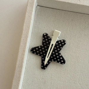 Star shaped hair clip with black and white polka dot patterns on a beige fabric tray
