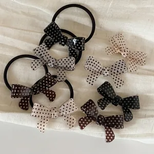 Polka dot bow hair clips and scrunchies set in neutral colors on a soft fabric background
