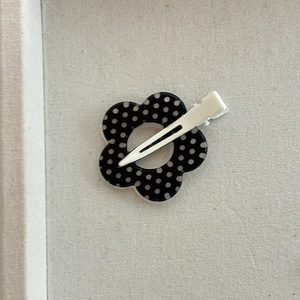 Detailed back view of a retro floral hair clip with black and white polka dots pattern