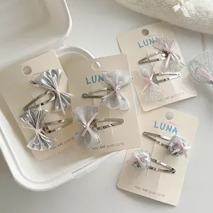 Detailed set of silver bow hair clips and sequin accessories on a display card