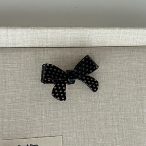 Close-up of a French style polka dot bow hair clip with smooth black fabric finish