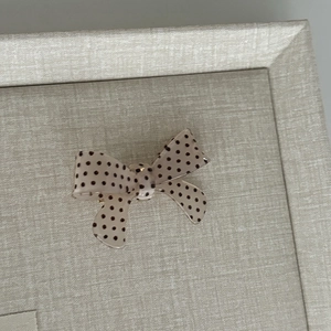Detailed view of a sweet polka dot bow hair clip on a minimalist jewelry display tray