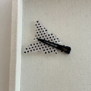 Detail of butterfly hair clip with black polka dots on white acrylic and metal clip