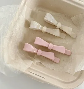 Detail of pink and pearly white bow-shaped hair clips made of glossy acetate material